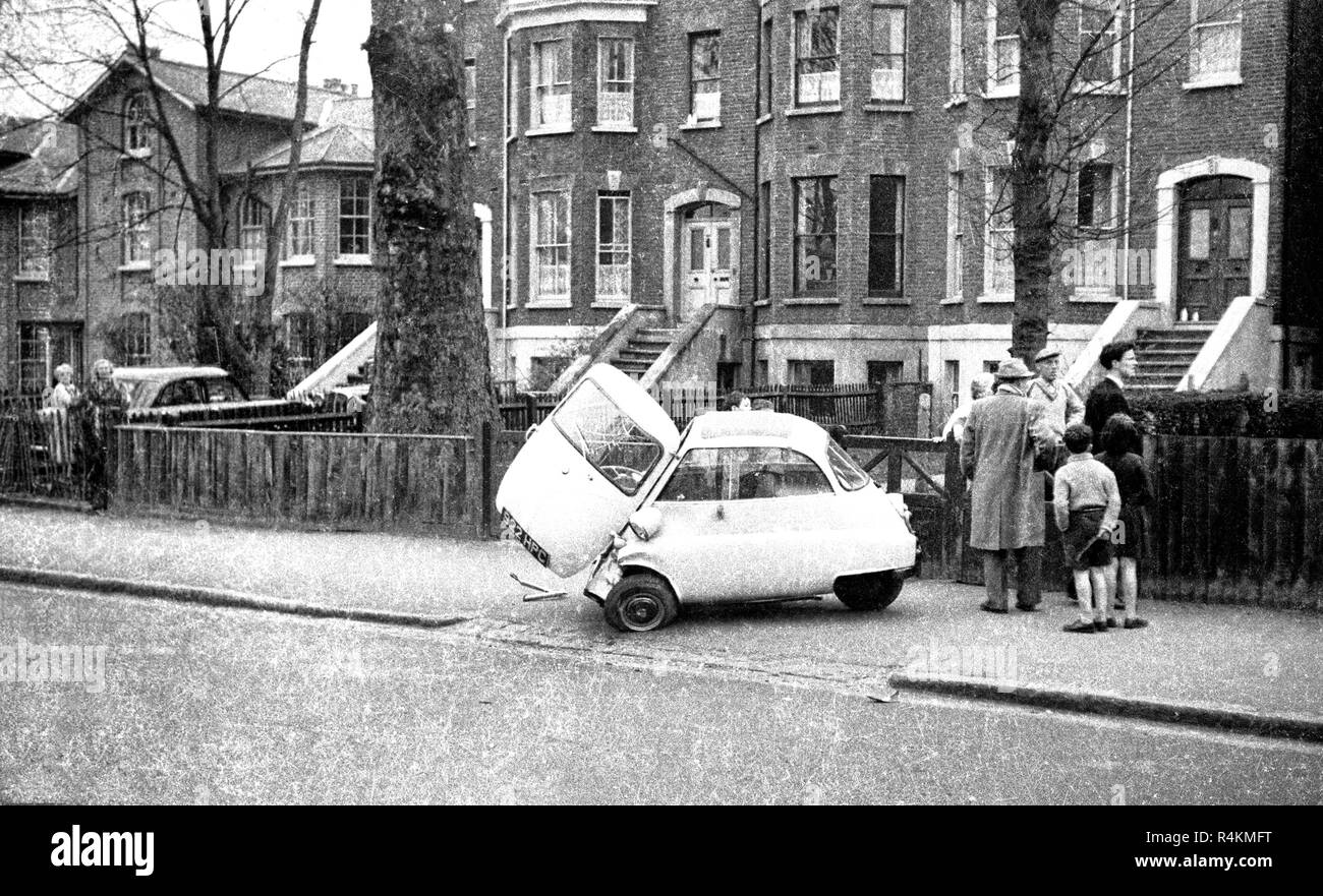 Eine BMW Isetta bubblecar bei einem Unfall auf dem Bürgersteig mit dem Fahrer und mehrere Zuschauer in Lee Road, Blackheath, SE3 geparkte beschädigt, 1959. Es gibt noch ein anderes Bild aus einem anderen Winkel mit einem Grundstück von der Nachkriegszeit prefabs im Hintergrund in Schwarz und Weiß, sowie eine eingefärbte Version. Stockfoto
