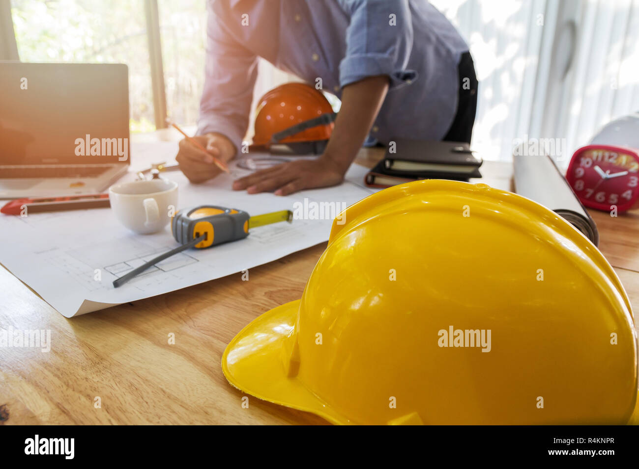 Helm auf hölzernen Schreibtisch mit dem Architekten Hintergrund Stockfoto