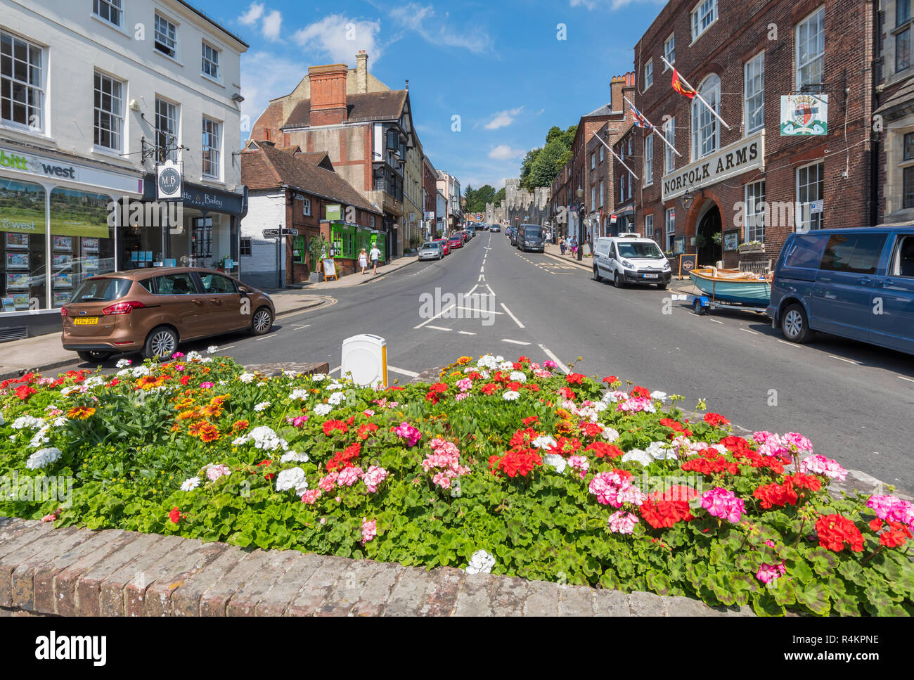 Blumenbeet und Geschäfte auf der Hohe Straße im Sommer in Arundel, West Sussex, England, UK. Arundel GROSSBRITANNIEN. Stockfoto