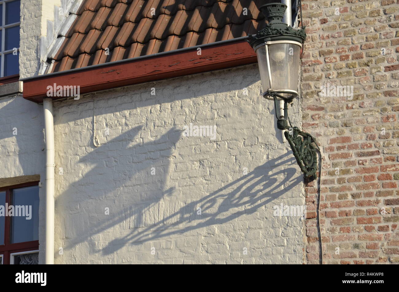 Ein traditionelles Licht Post und ihre Schatten auf einen flämischen Stil Gebäude in Brügge, Belgien. Stockfoto