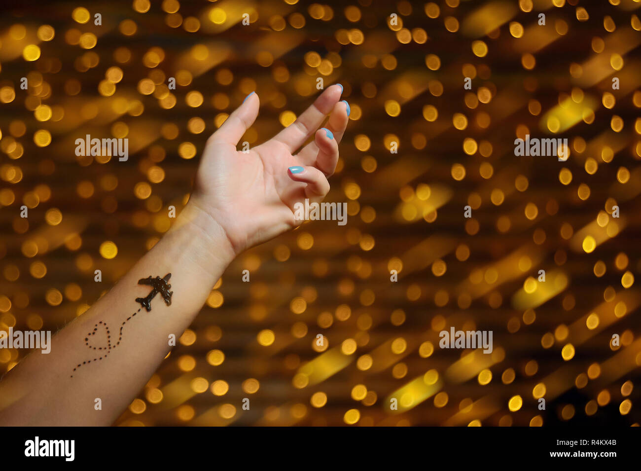 Hand mit Flugzeug und Herz tattoo bei unscharfer Girlande Hintergrund