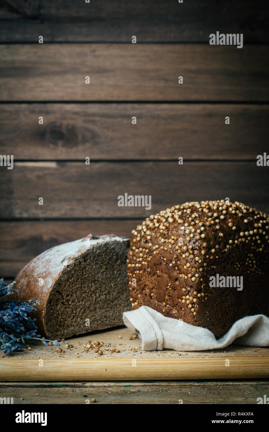 Gebackene hausgemachte Roggen dunkles Brot mit Koriander und Lavendel auf rustikalen Holztisch Hintergrund. Kopieren Sie Platz. Stockfoto