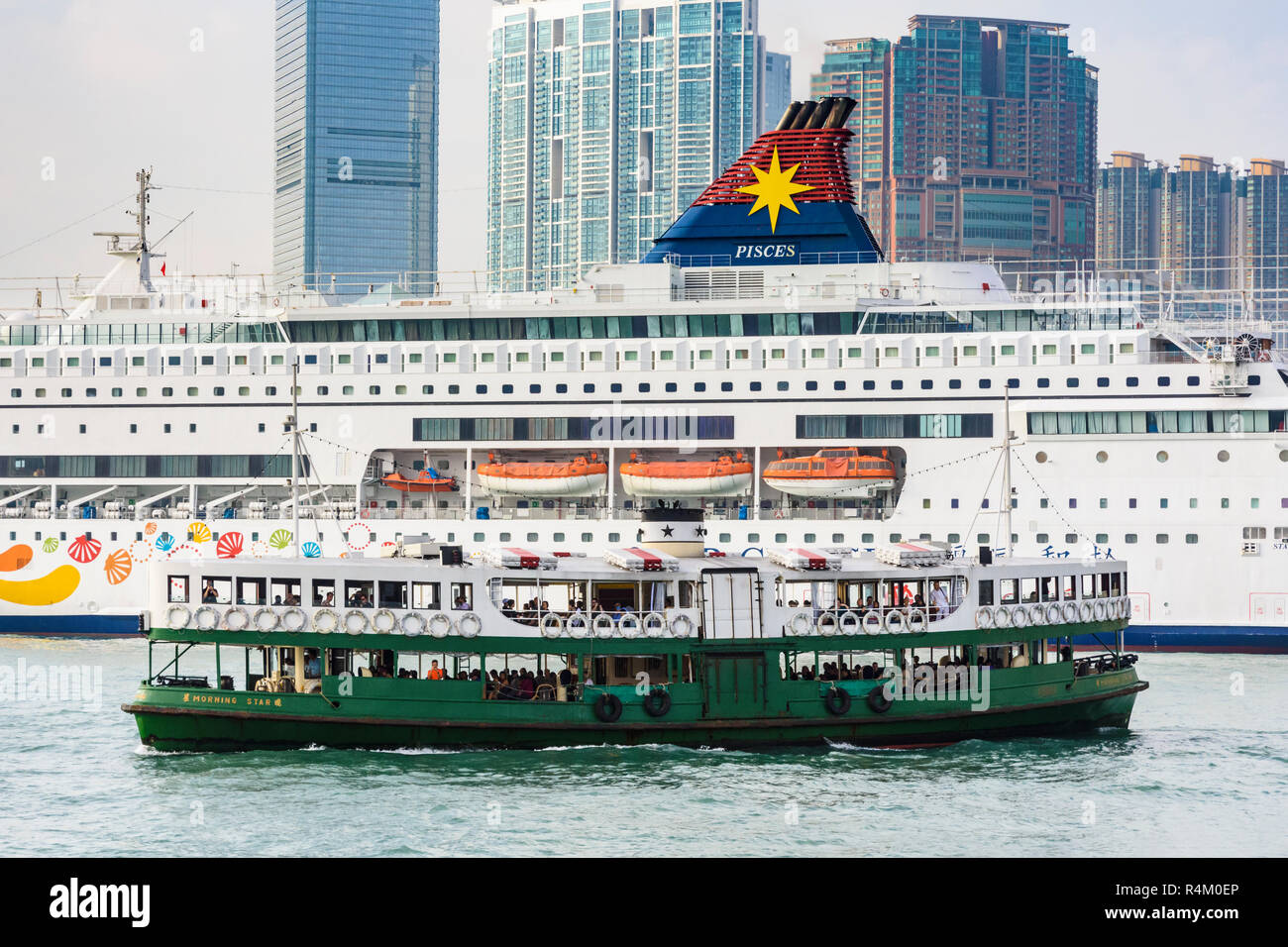 Einen traditionellen grünen und weißen Star Ferry vor einem großen Kreuzfahrtschiff in Victoria Harbour und Hong Kong Stockfoto