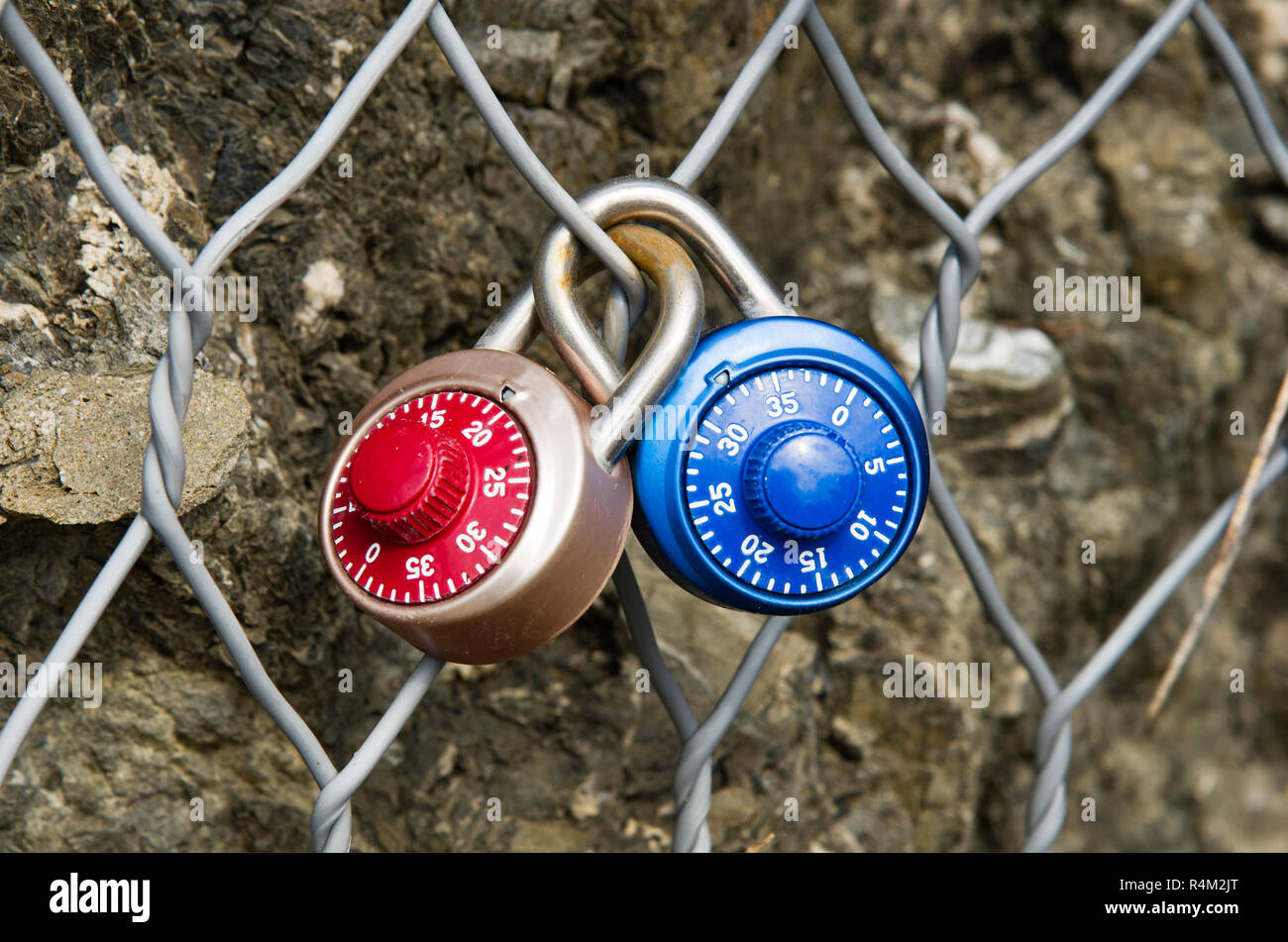 Zwei Vorhängeschlösser Kombination geschlossen auf einem Metallgitter Stockfoto