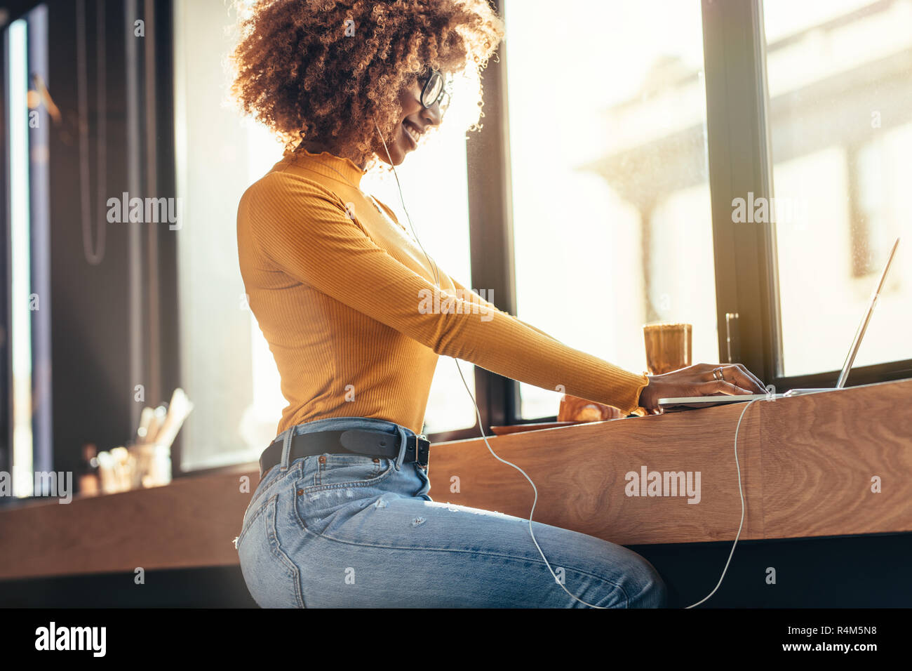 Seitenansicht eines lächelnden afro-amerikanische Frau, die Arbeiten am Laptop während in einem Café sitzen. Frau Unternehmer ihre Arbeit Verwaltung auf Laptop im Sitzen Stockfoto