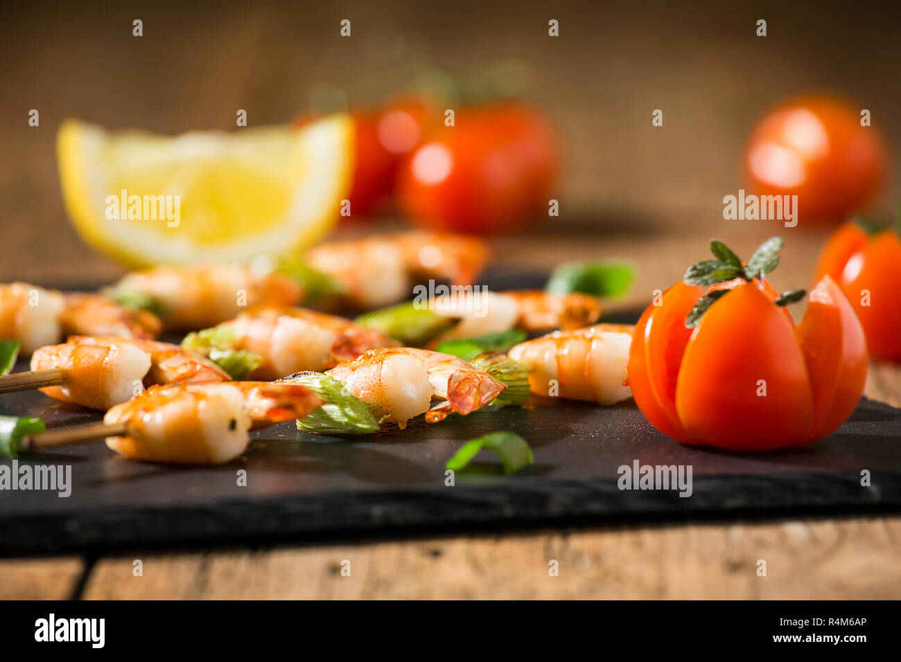 Nahaufnahme von Garnelen Spieße mit Tomaten und Kräutern auf einem Stein Stockfoto