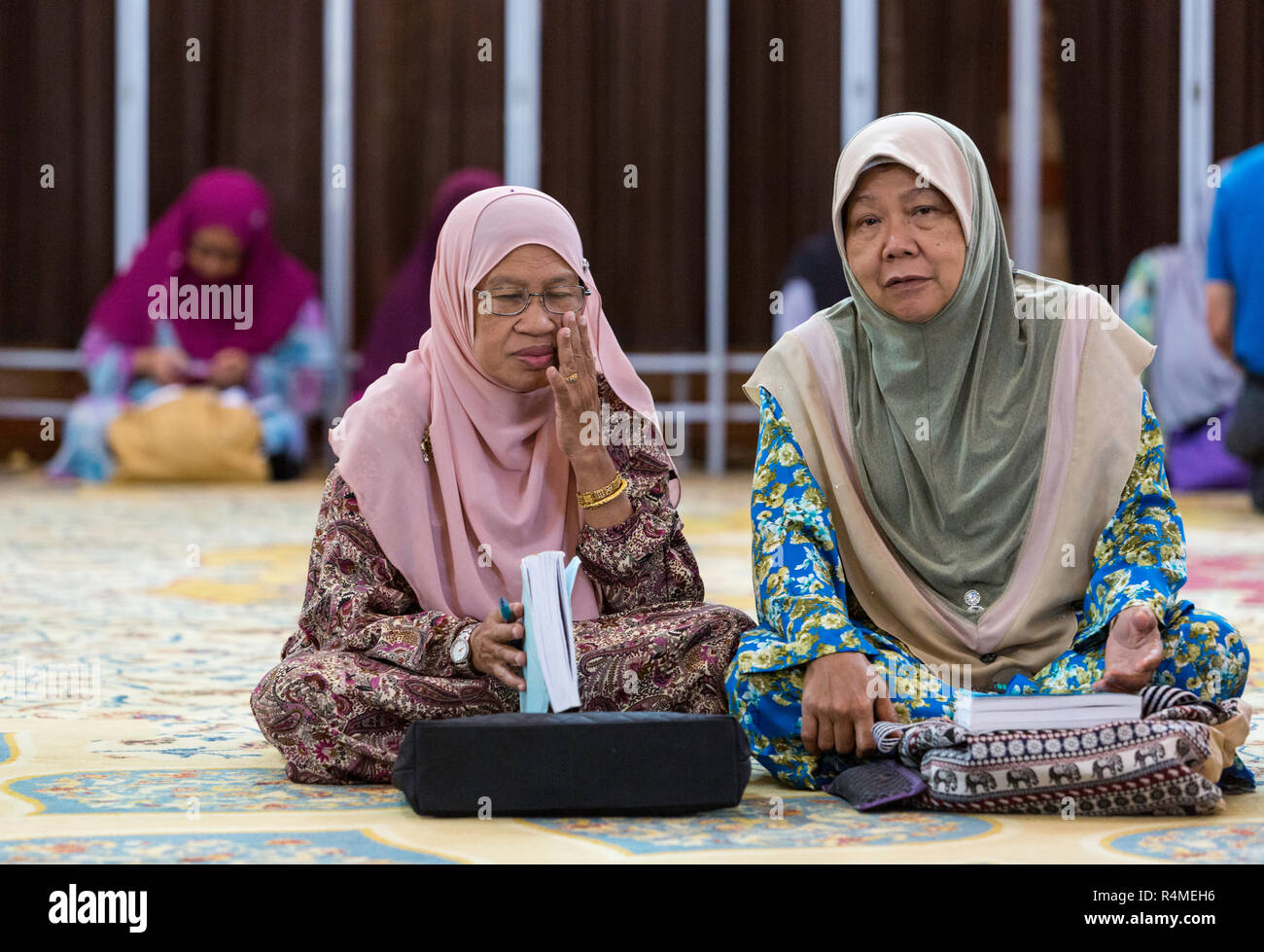 Muslimische Frauen warten zu beginnen Quranic Studie Klasse mit ihren Imam, Ubudiah Moschee, Kuala Kangsar, Malaysia. Stockfoto