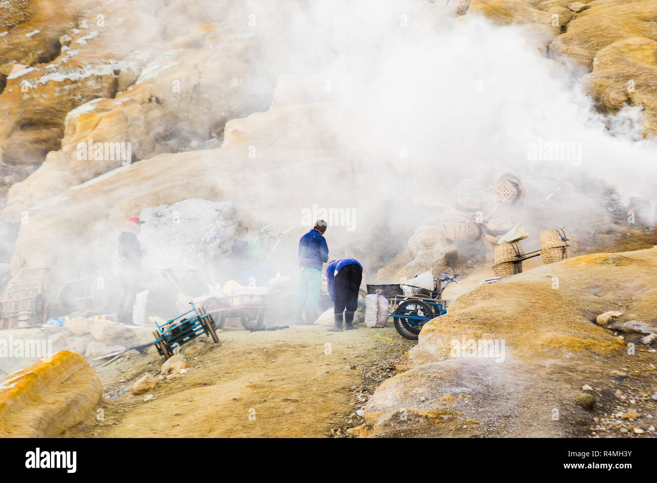 Die Menschen nehmen Schwefel Felsen in der Nähe von gefährlichen Wolken des Ijen Krater Berg, Banyuwangi, Indonesien Stockfoto