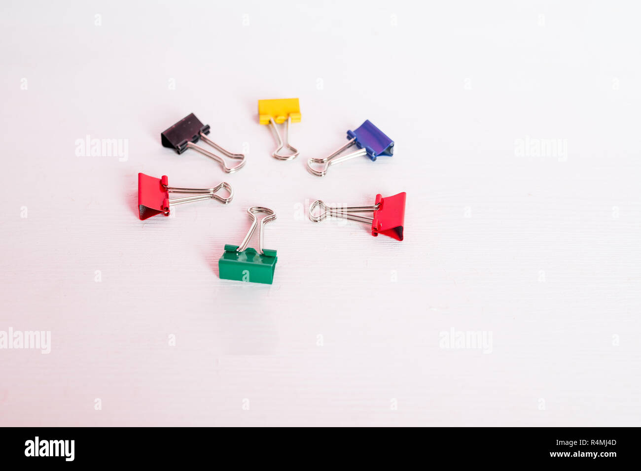 Bunte Binder Clip auf weißem Hintergrund. Sechs Büroklammern als Kreis isoliert. Platz kopieren. Schulbedarf, Bürobedarf, zurück in die Schule, Kunst und Handwerk Material Stockfoto