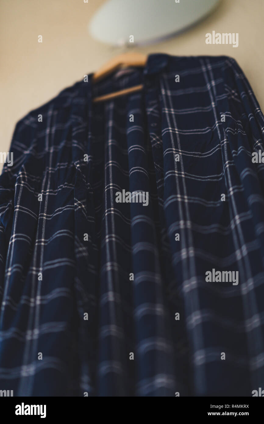 Blaues T-Shirt mit Streifen an der Wand im Wohnzimmer - isoliertes Objekt, teilweise unscharf, Vintage Film bearbeiten Stockfoto