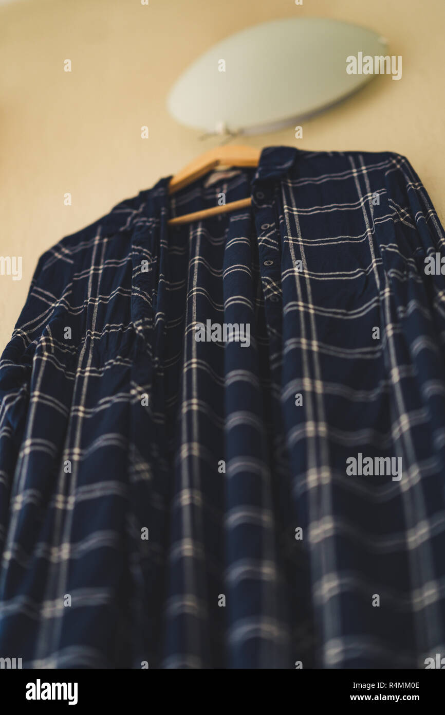 Blaues T-Shirt mit Streifen an der Wand im Wohnzimmer - isoliertes Objekt, teilweise unscharf, Vintage Film bearbeiten Stockfoto