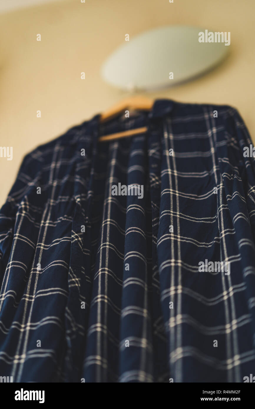Blaues T-Shirt mit Streifen an der Wand im Wohnzimmer - isoliertes Objekt, teilweise unscharf, Vintage Film bearbeiten Stockfoto