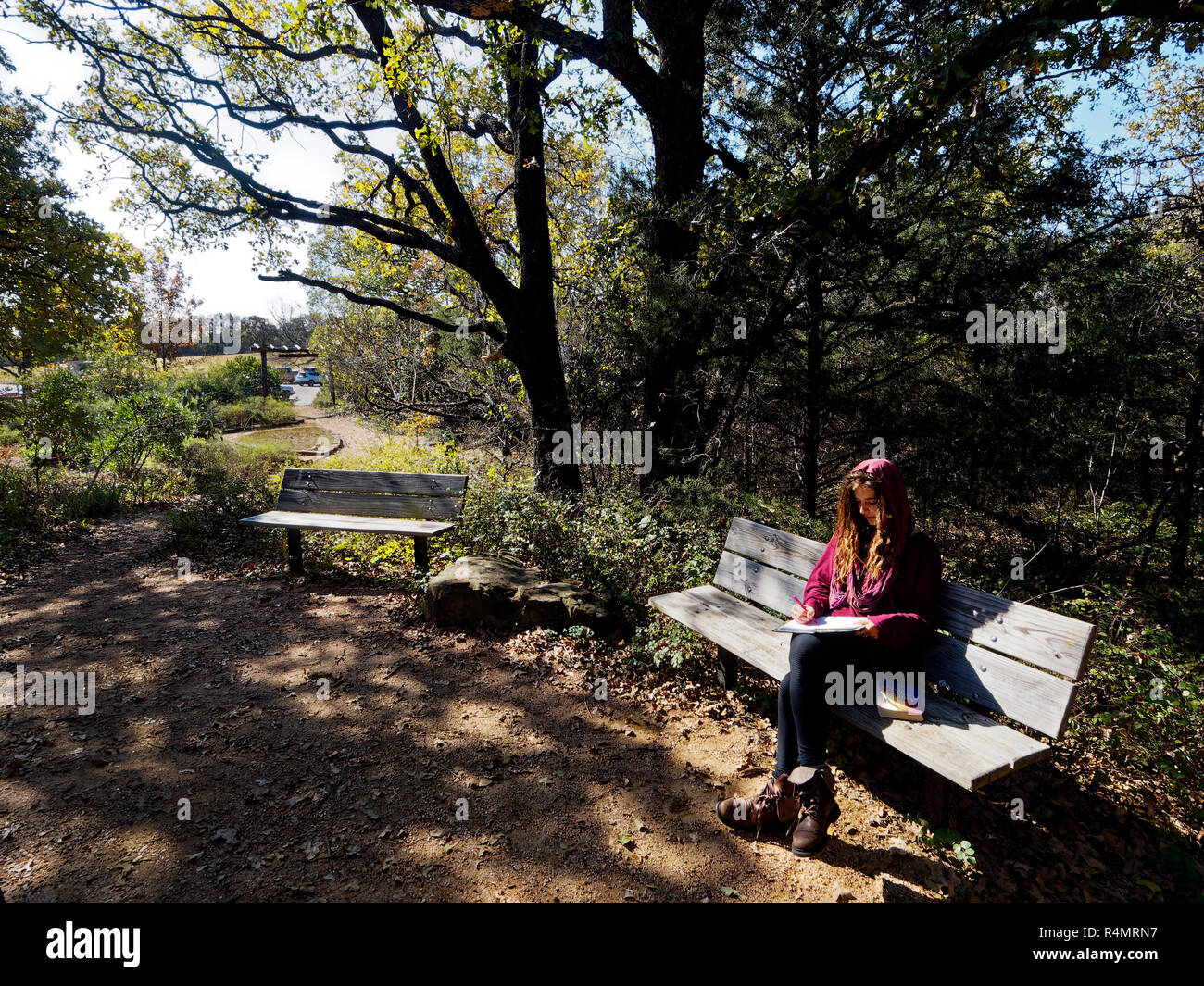 Aus abrufen und lesen oder allein Schreiben in einem städtischen Park kontrastiert mit dem Beton und Lärm des städtischen Lebens. Stockfoto