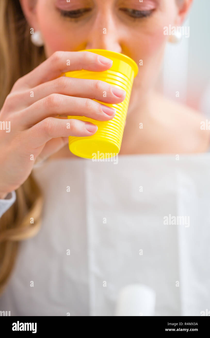 Patienten spülen Mund mit einer Tasse Wasser beim Zahnarzt Stockfotografie
