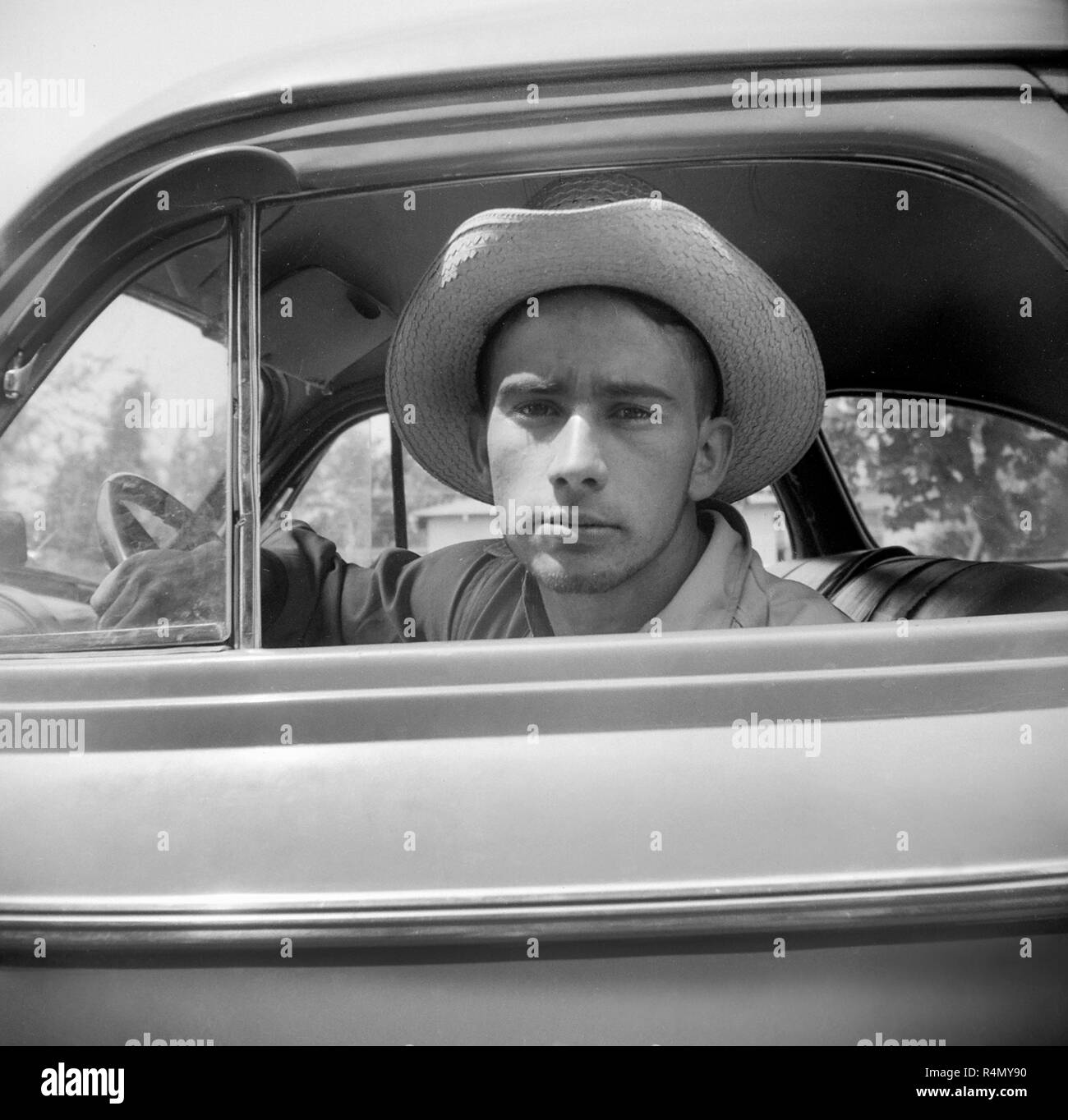 Ein junger Mann mit einem Cowboyhut schaut aus seinem Auto Fenster, Ca. 1955. Stockfoto