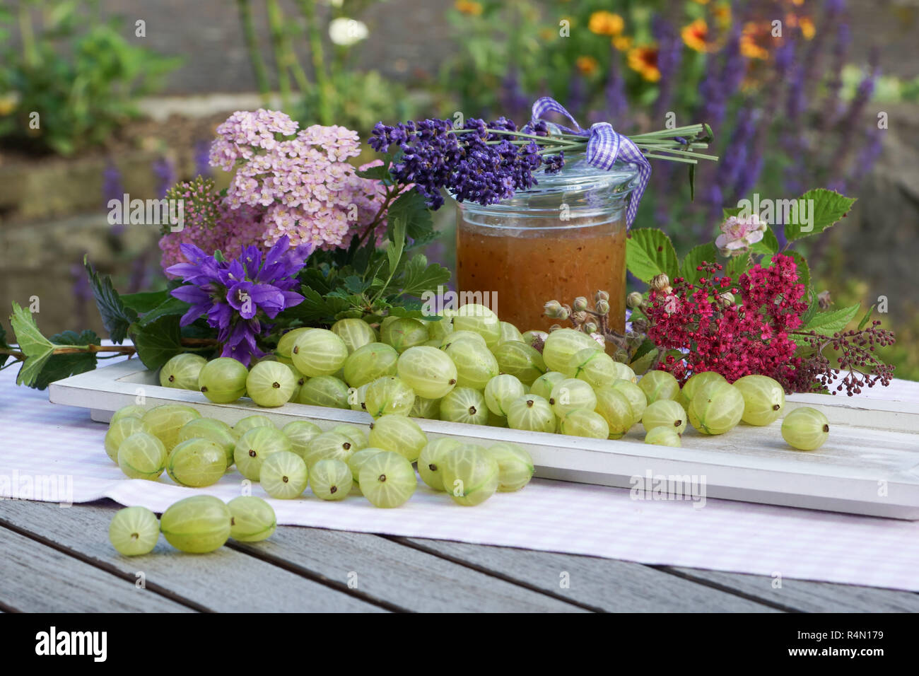 Sommer Ambiente mit stachelbeeren auf Holz Fach liebevoll mit Blumen und Jam jar eingerichtet Stockfoto