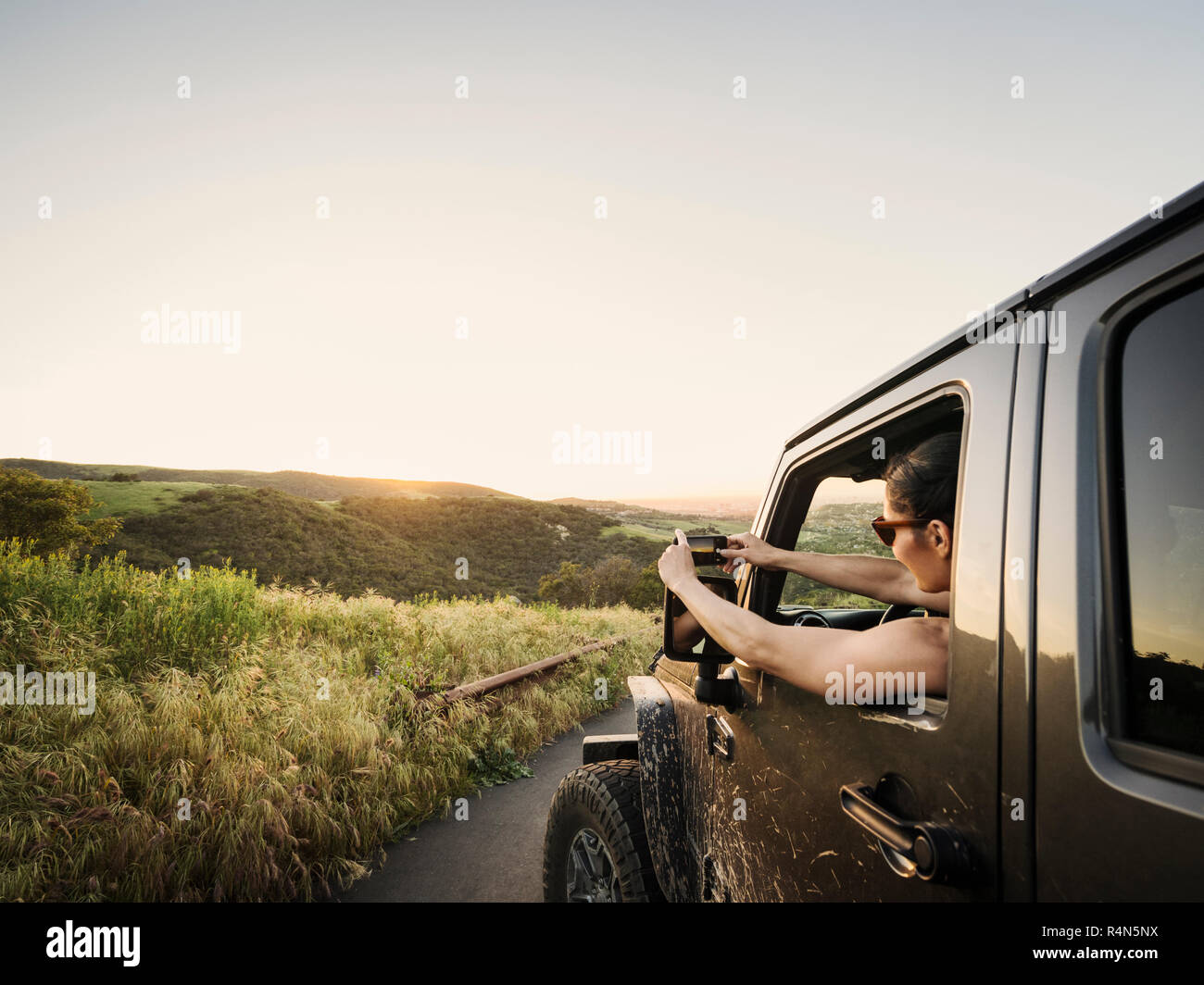 Frau in Off Road Fahrzeug fotografiert Sonnenuntergang Stockfoto