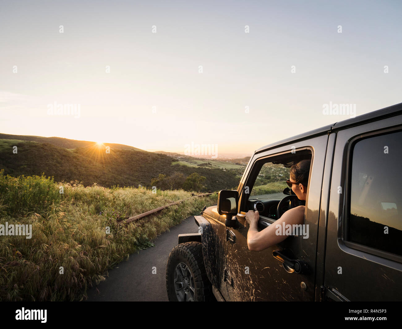 Frau in Off Road Fahrzeug bei Sonnenuntergang Stockfoto