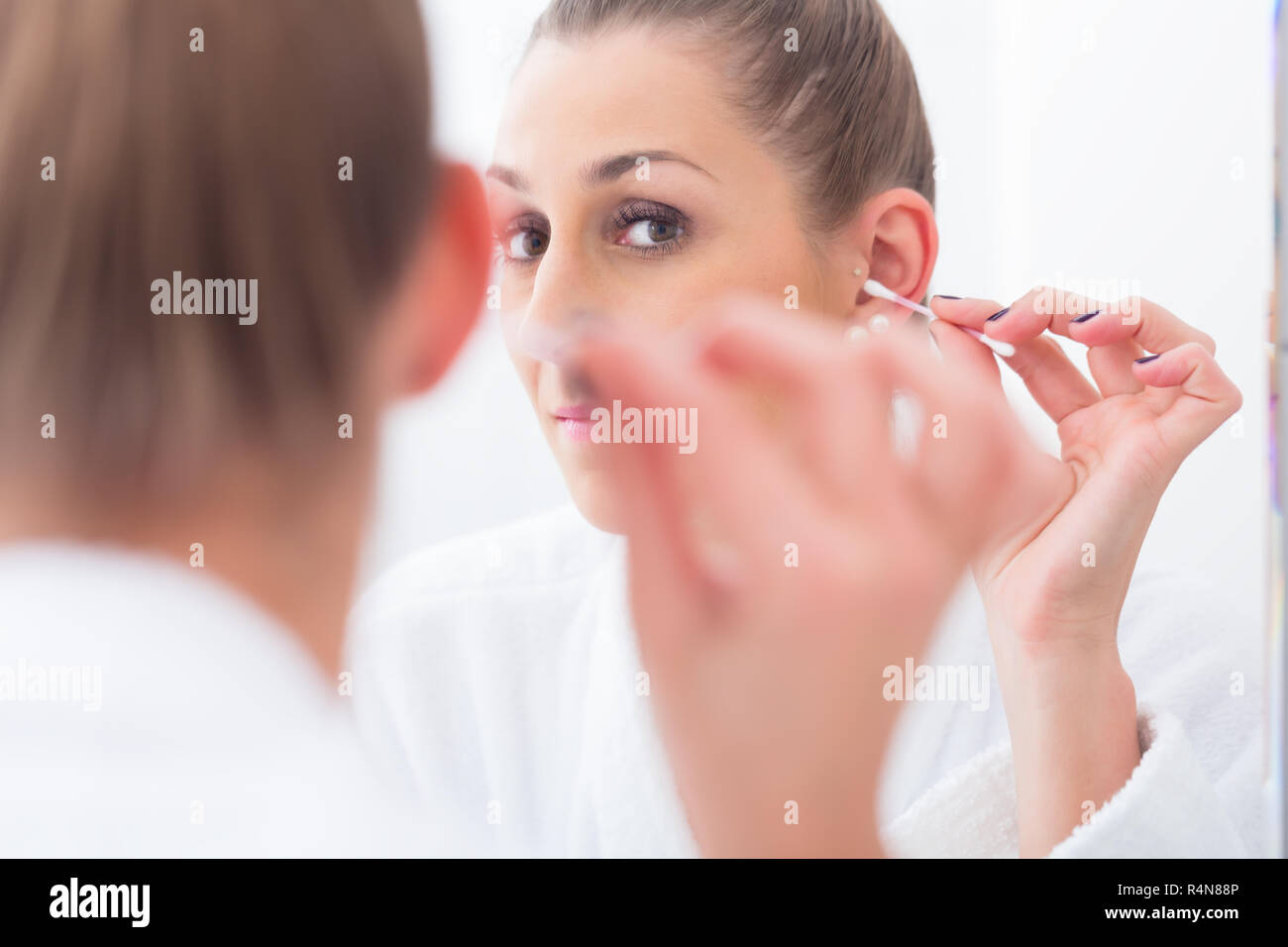 Frau Reinigung ihre Ohren mit Wattestäbchen Stockfoto