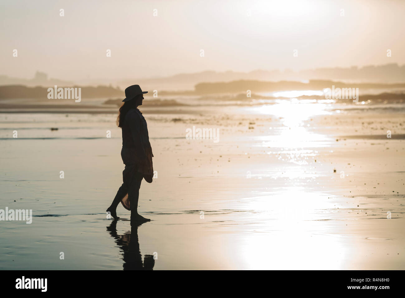 Silhouette der Frau am Strand bei Sonnenuntergang Stockfoto