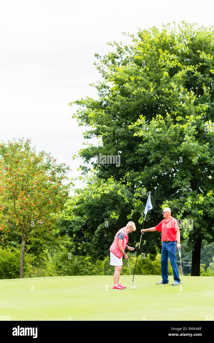 Ältere Frau und Mann spielt Golf Putting auf Grün Stockfoto