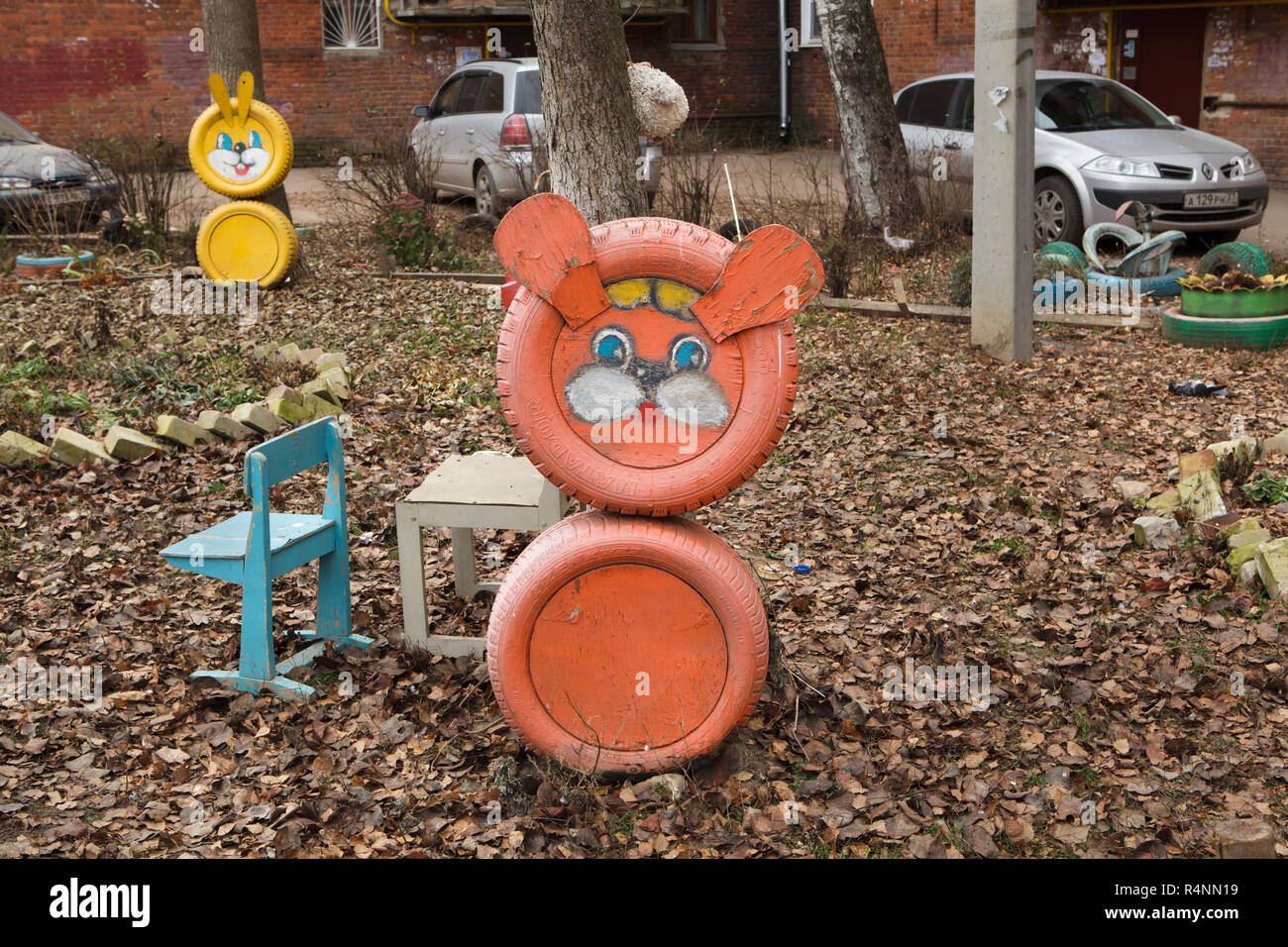 Unbekannter orange Kreatur, wahrscheinlich ein Löwe oder ein Bär, von Altreifen auf dem Spielplatz des Kindes in Ulan-Ude, Russland. Die gelbe Hase auch von Altreifen sind im Hintergrund zu sehen. Achtung: Dieses Bild ist ein Teil von einem fotoessay von 18 Fotos mit den gleichen Spielplatz. Stockfoto