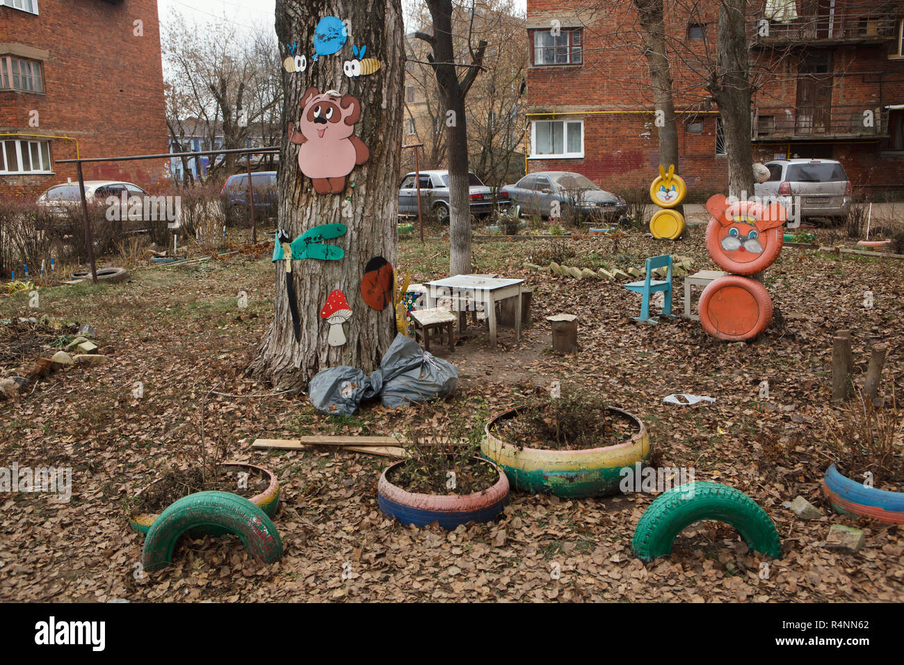 Der Kinderspielplatz in Ivanovo, Russland. Winnie-the-Pooh und die Bienen, wie sie in der Sowjetischen Anpassung angezeigt werden, basieren auf den Baum über die Libelle dargestellt, das fly Agaric und der Marienkäfer. Die gelbe Hasen und die nicht identifizierten orange Kreatur, wahrscheinlich ein Löwe oder ein Bär, von Altreifen werden in den Hintergrund, während die Blumenbeete auch von Altreifen sind im Vordergrund gesehen. Achtung: Dieses Bild ist ein Teil von einem fotoessay von 18 Fotos mit den gleichen Spielplatz. Stockfoto
