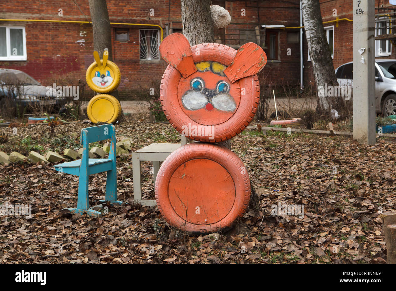 Unbekannter orange Kreatur, wahrscheinlich ein Löwe oder ein Bär, von Altreifen auf dem Spielplatz des Kindes in Ulan-Ude, Russland. Die gelbe Hase auch von Altreifen sind im Hintergrund zu sehen. Achtung: Dieses Bild ist ein Teil von einem fotoessay von 18 Fotos mit den gleichen Spielplatz. Stockfoto