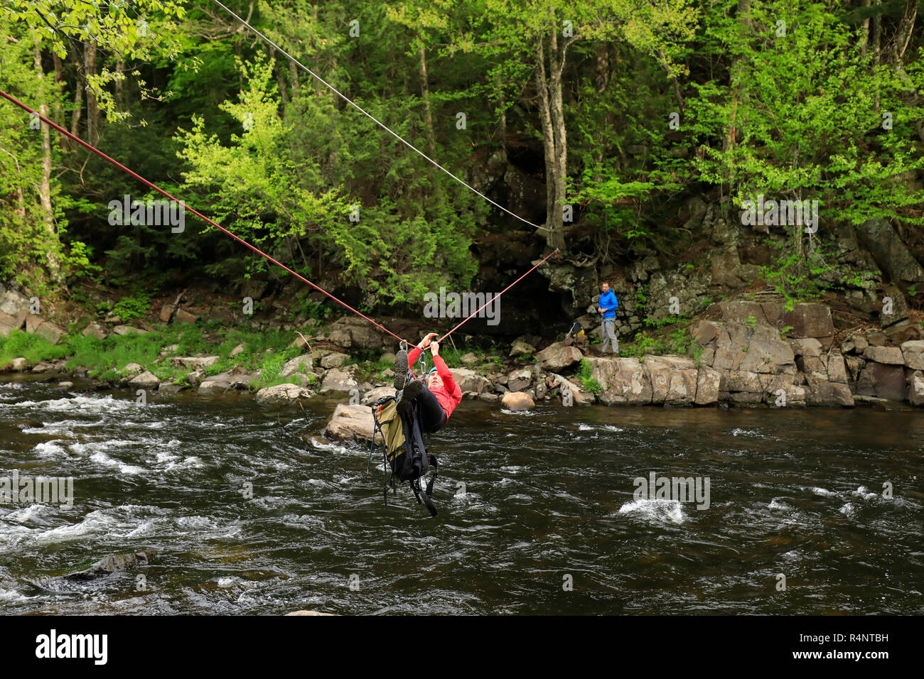 Kletterer Verfahren über die Au Sable River, um Zugang zum Klettern einer Route auf Moss Klippe über Wilmington Kerbe, Adirondack Mountains, New York State, USA Stockfoto