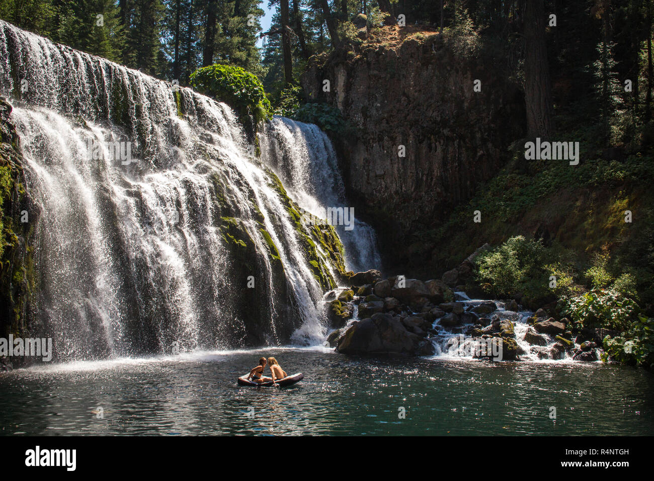 Fernsicht auf Paar in Floß auf dem Wasser schwimmend in der Nähe von Wasserfall, Â McCloudÂ Fluss, Kalifornien, USA Stockfoto