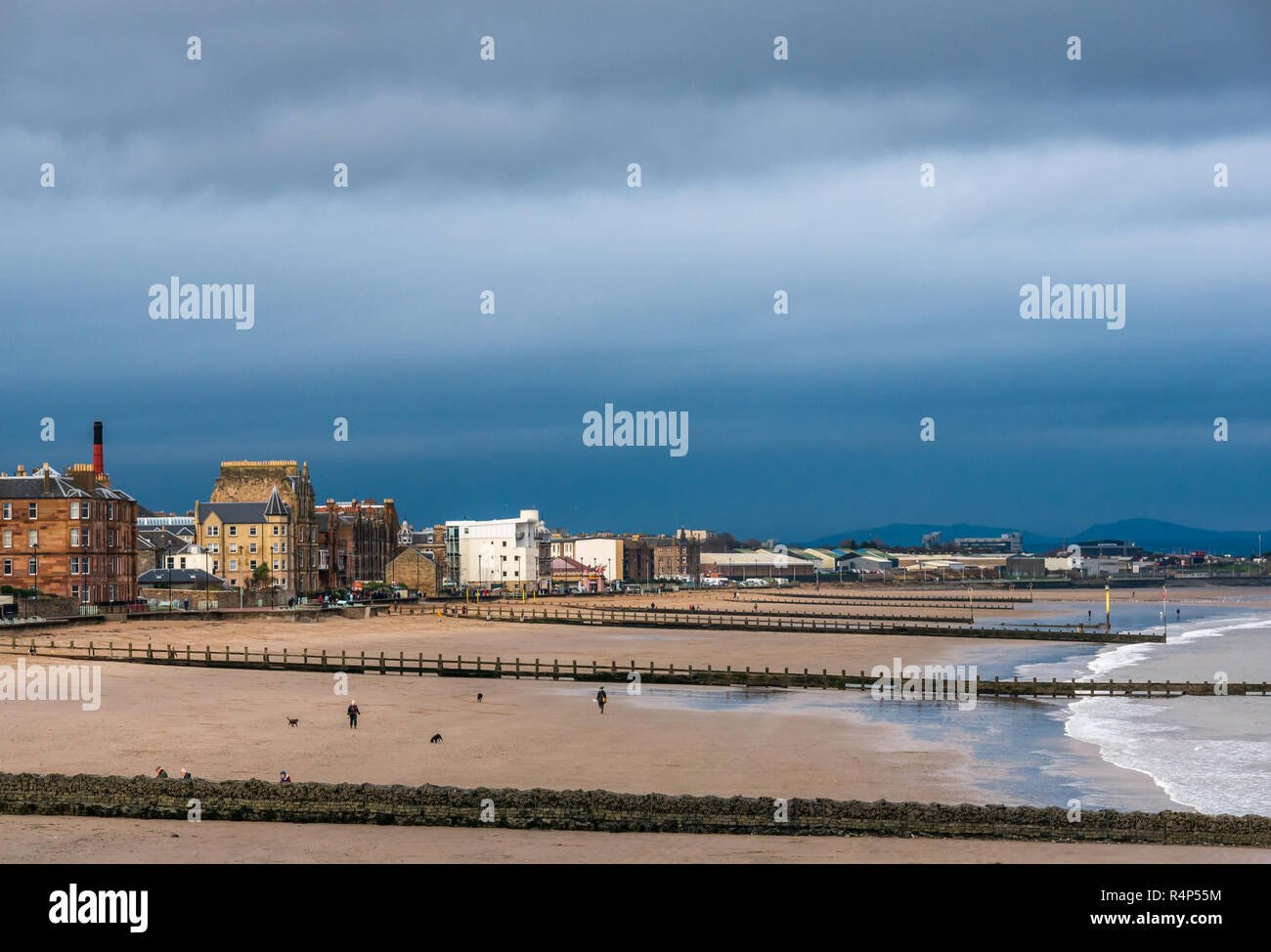 Portobello, Edinburgh, Schottland, Vereinigtes Königreich, 28. November 2018. UK Wetter: Dunkle Sturmwolken über Leute, die Hunde am Strand an der Portobello als Sturm Diana Ansätze. Der Strand verfügt über buhnen am Ufer zu schützen. Stockfoto
