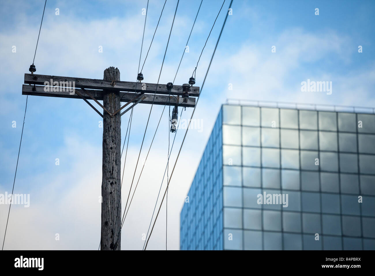Electric power line, alt und veraltet, auf einem morschen hölzerne Stange, und die Energieversorgung zu einem modernen Bürogebäude in der Innenstadt von Ottawa, Ontario Stockfoto