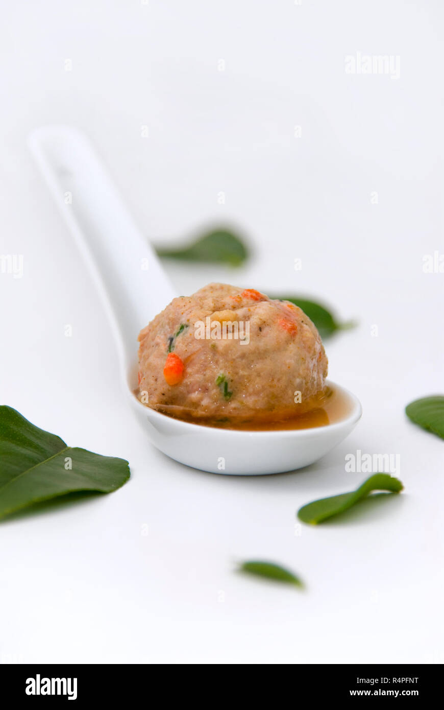 Schweinefleisch meatball in kafir Kalk blatt Fleischbrühe serviert auf einem kleinen weißen Löffel Stockfoto