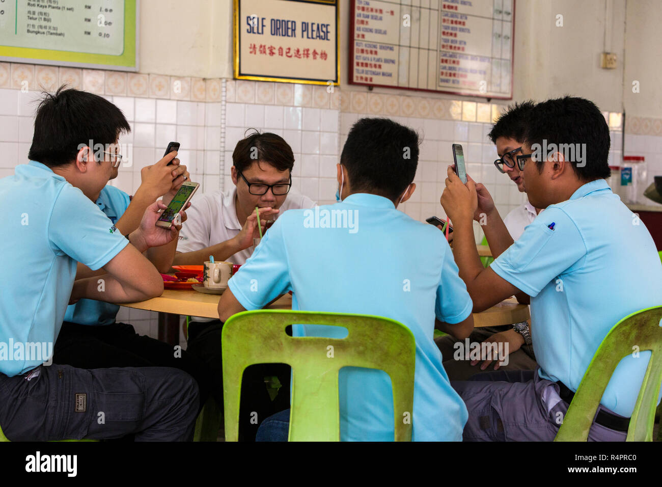 Junge malaysischen Männer treffen zum Mittagessen, mit Handys, Taiping, Malaysia. Stockfoto