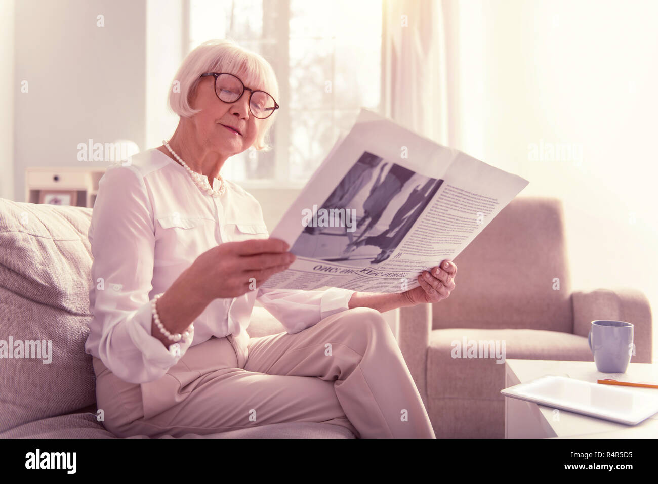 Neugierige alte Dame aufmerksam lesen eine interessante Zeitung Stockfoto