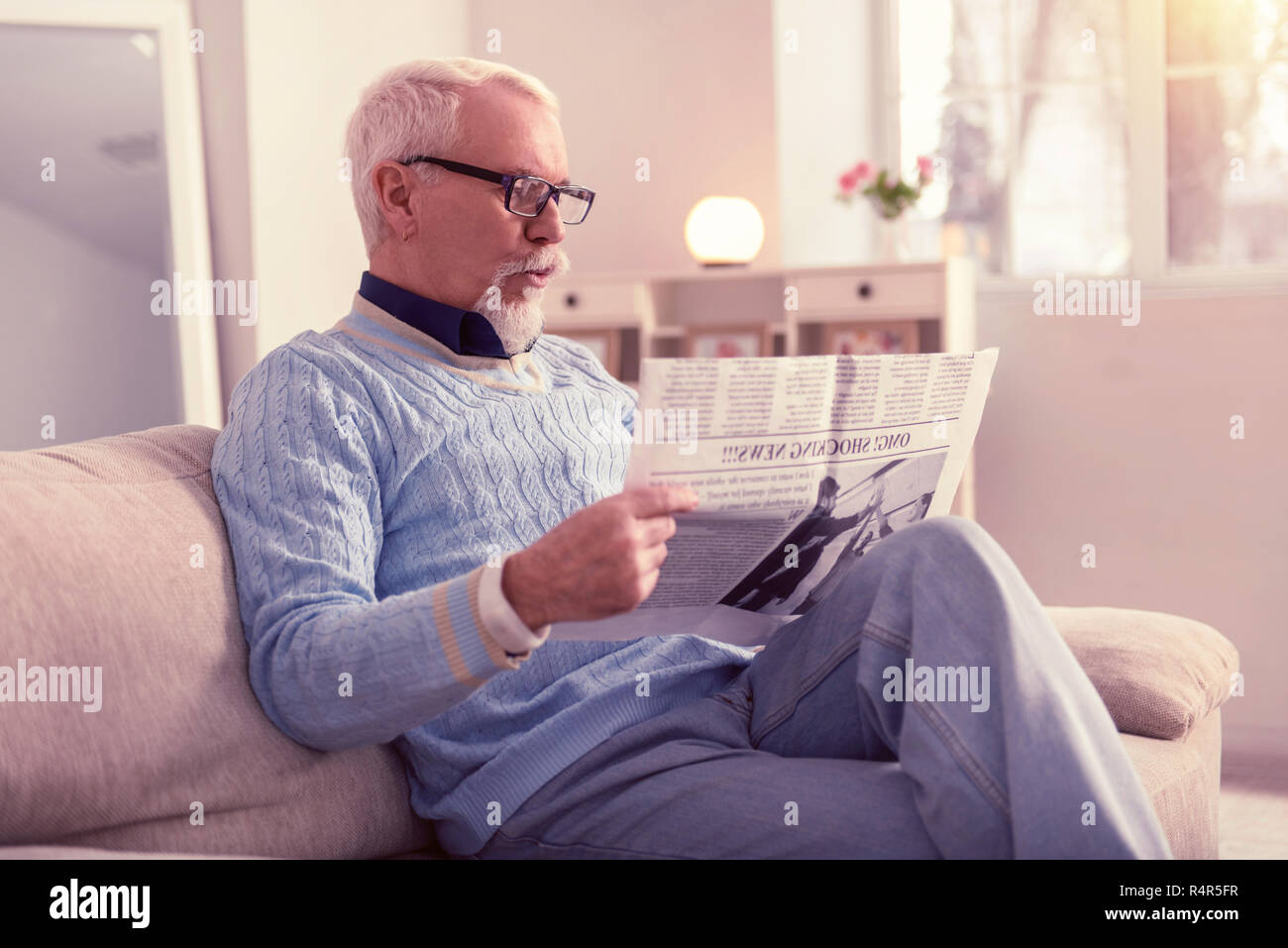 Neugierig Senior mit Materialien, die in der Zeitung überrascht Stockfoto