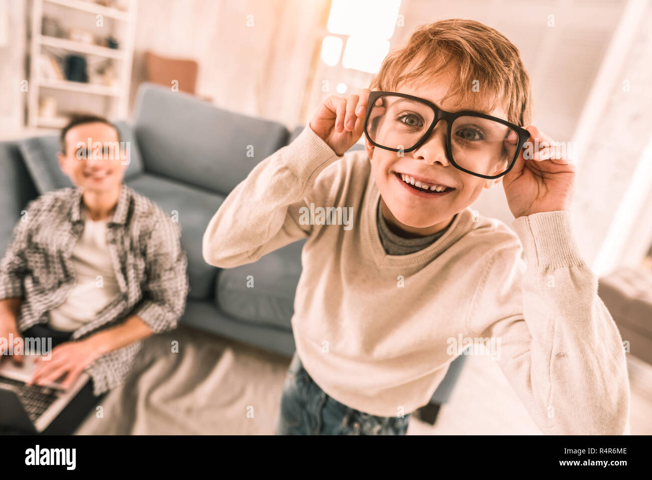 Little Boy amüsante selbst durch die Brille seines Vaters trägt. Stockfoto
