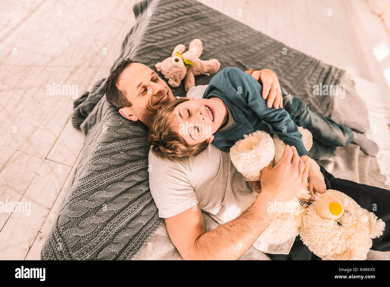 Pflege Mann liebevoll seinen Sohn umarmt, während er auf eine Matratze. Stockfoto