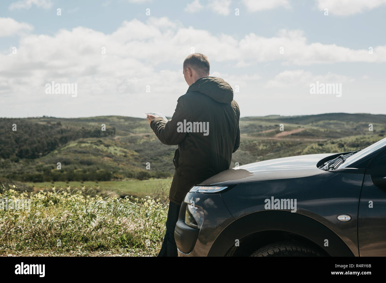 Eine touristische Mann neben das Auto sieht auf der Karte der Bereich für weitere Reisen. Stockfoto