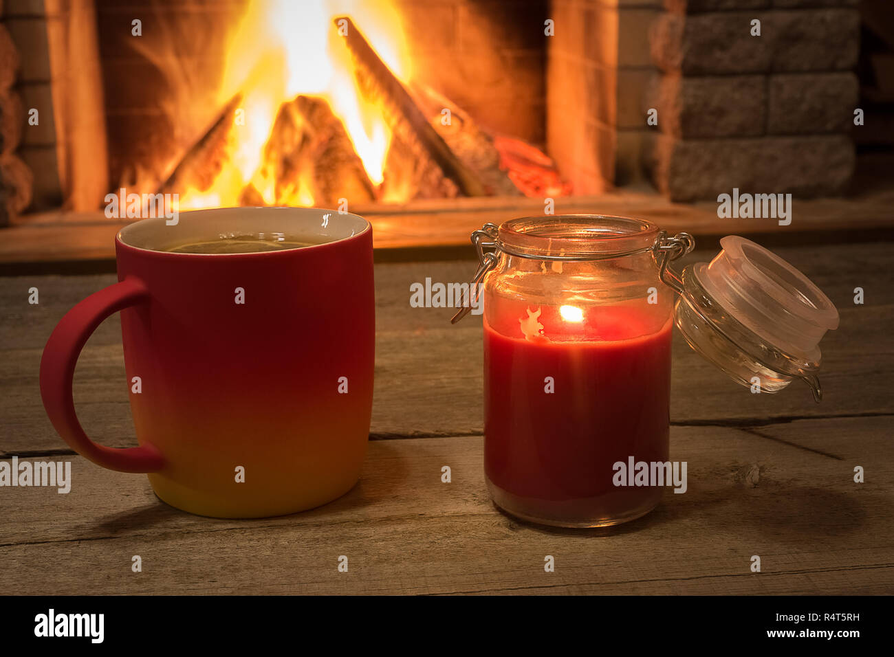 Becher mit heißem Tee und Kerzenschein in der Nähe von gemütlichem Kamin, im Landhaus, winter Urlaub, horizontal. Stockfoto