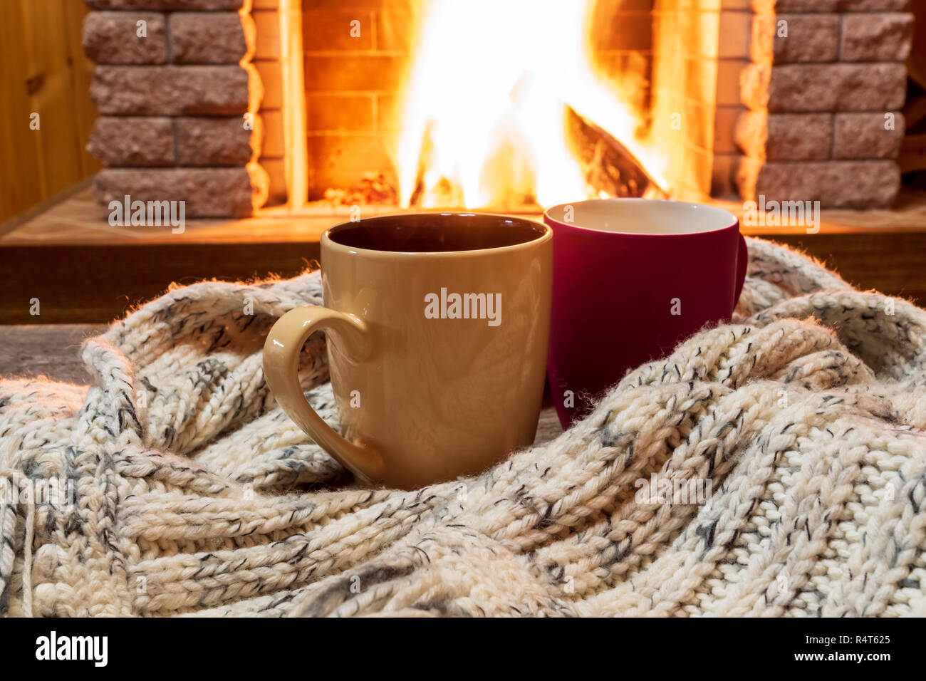 Zwei Becher mit heißem Tee und gemütlich warmen Schal in der Nähe von Kamin, im Landhaus, winter Urlaub, horizontal. Stockfoto