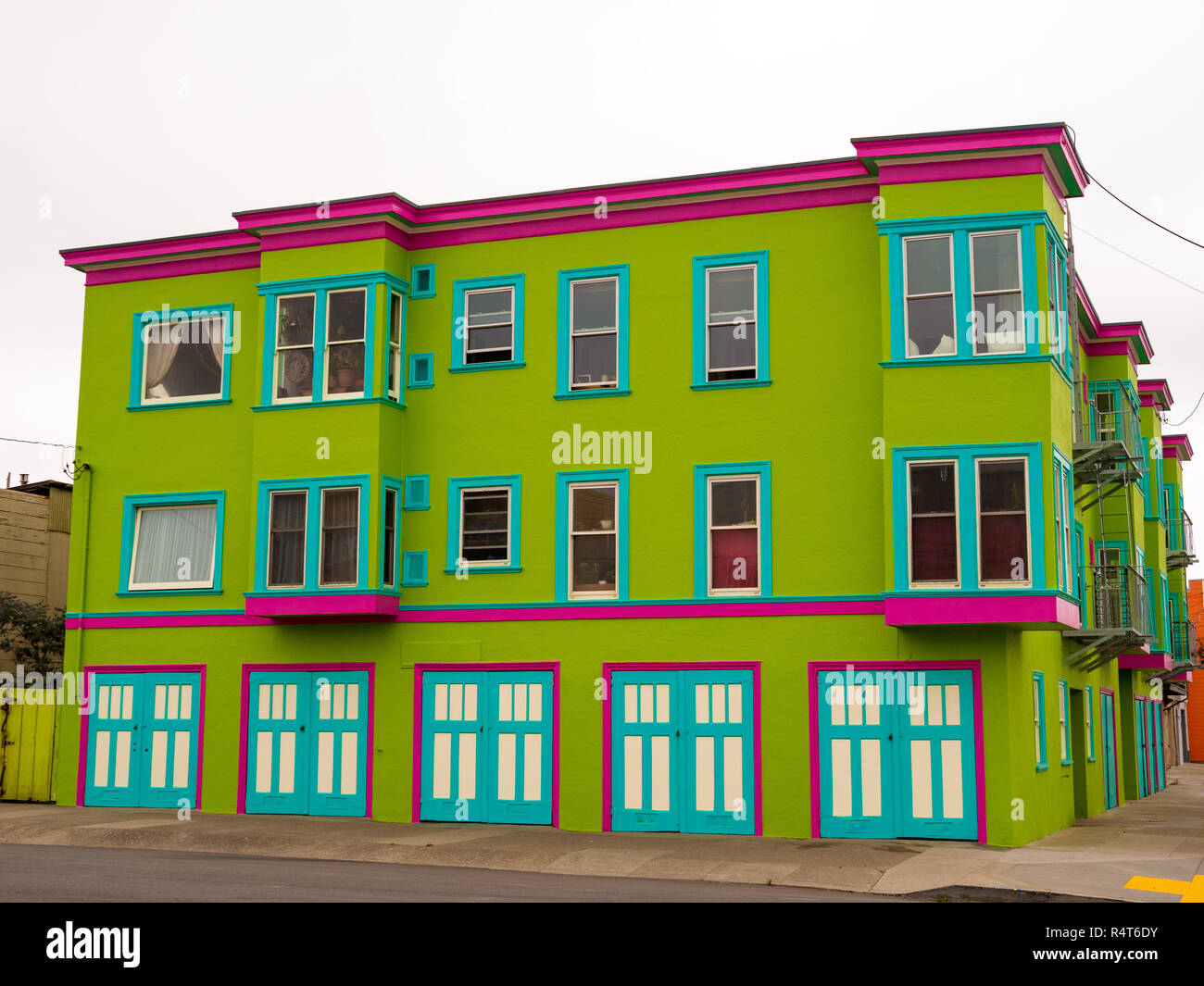 Grün, Pink und teal Gebäude in der Nachbarschaft bei bedecktem Himmel Stockfoto
