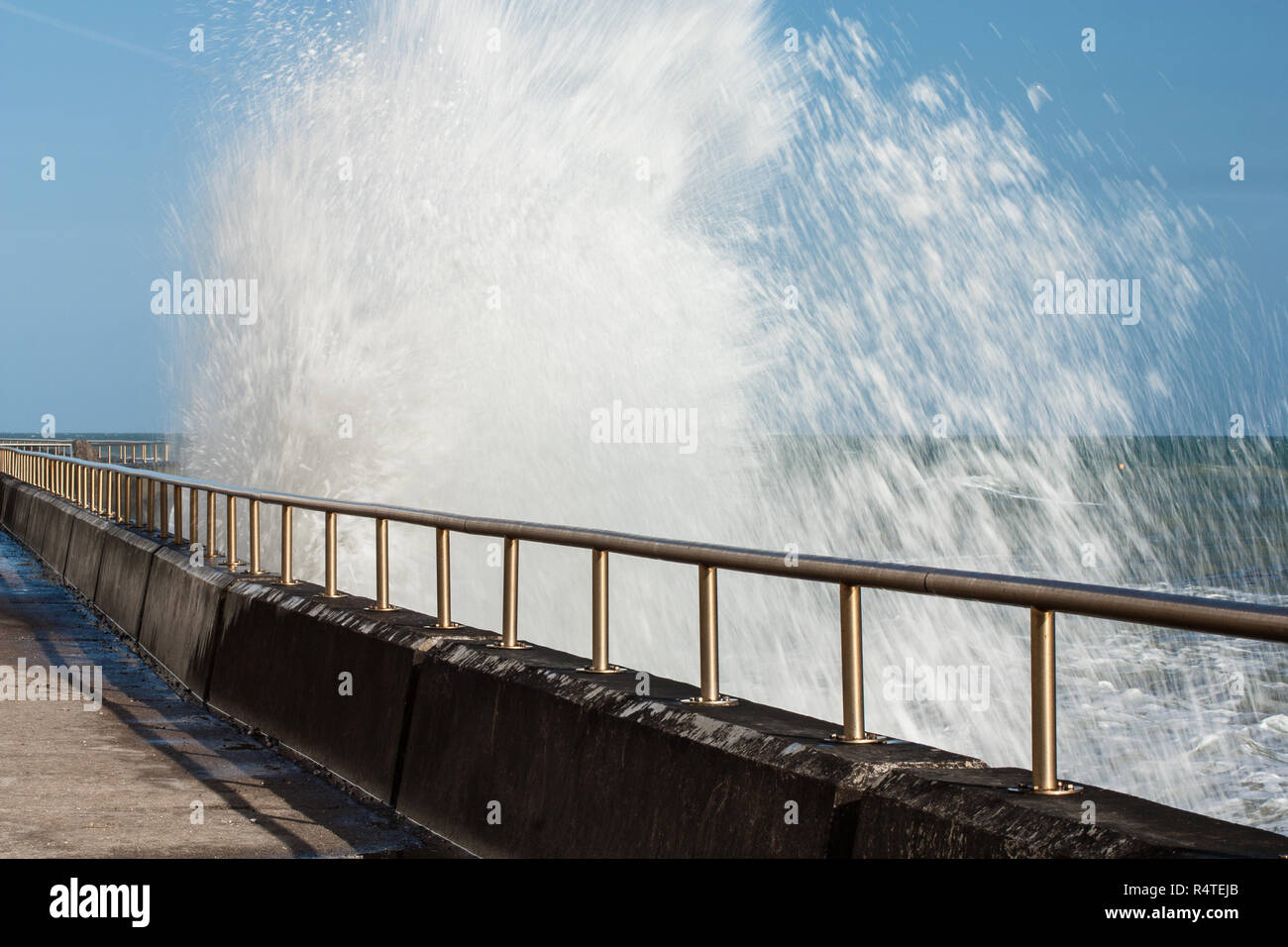 Die Wellen gegen den Beton Gehweg, der Spencer Court gehen, East Sussex Stockfoto