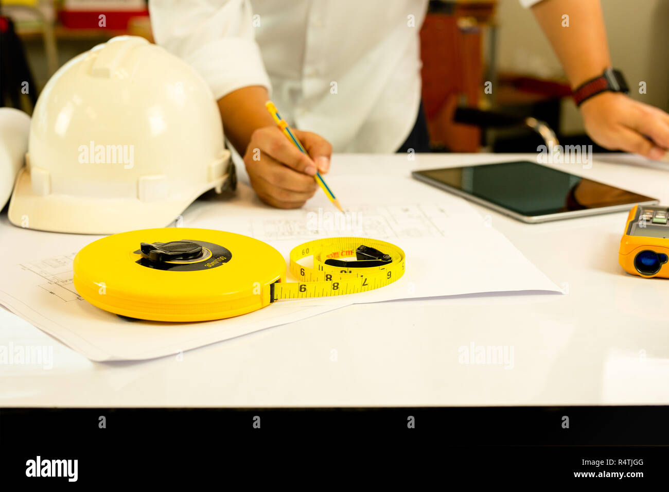 Hand des Architekten arbeiten an Blaupause mit Tablet-PC auf dem Tisch. Stockfoto