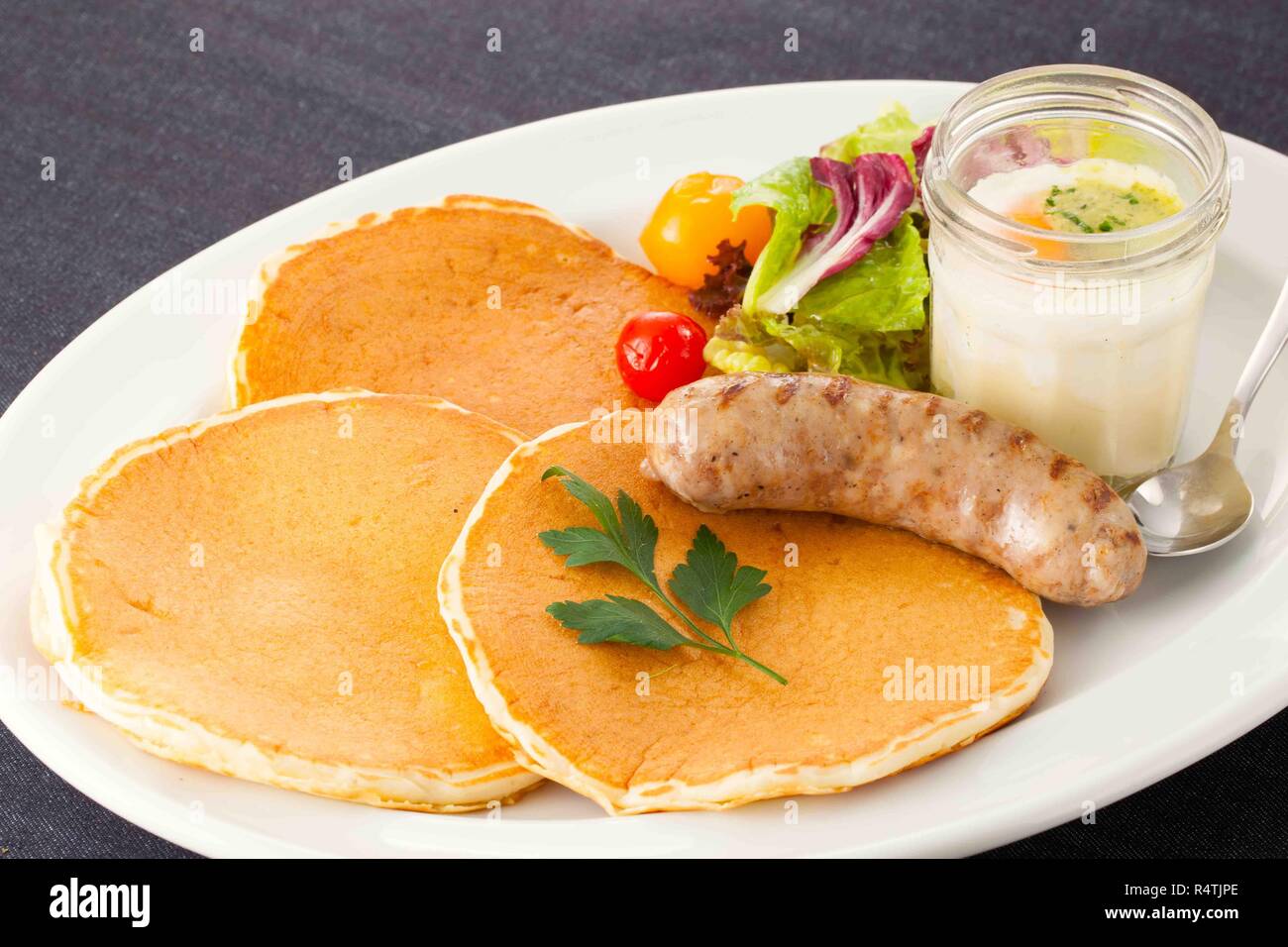 Gebratene Würstchen mit Salat, Brot und Obst auf weißem Teller Stockfoto