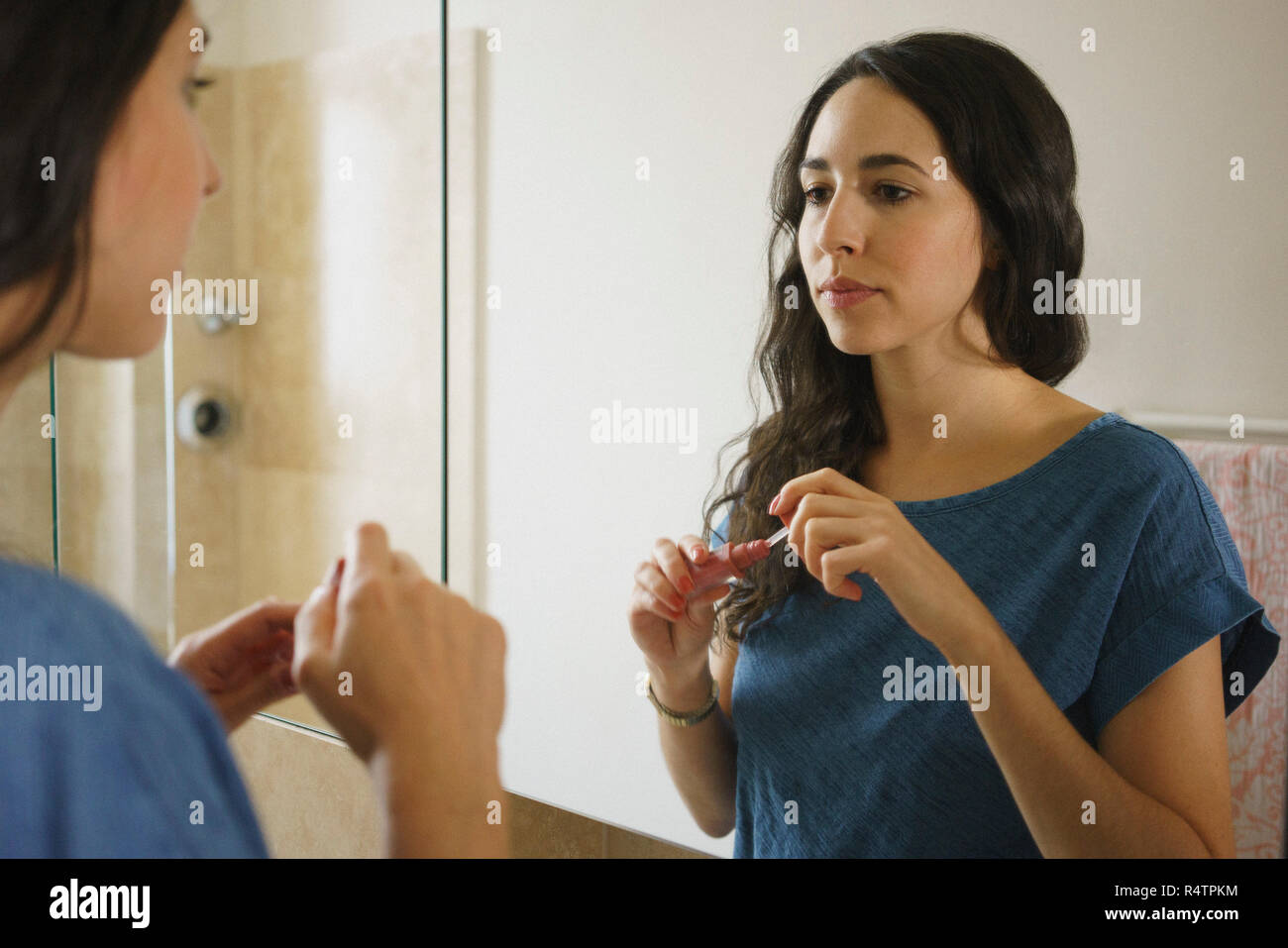 Frau Anwendung Lip Gloss in Bad Spiegel Stockfoto