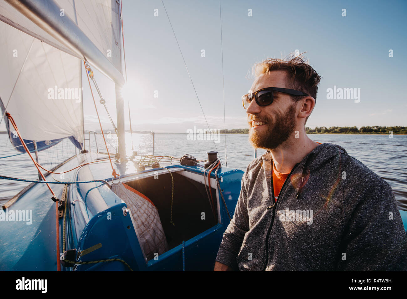 Erfolgreiche junge bärtige Mann segeln Portrait bei Sonnenaufgang auf dem Boot Stockfoto