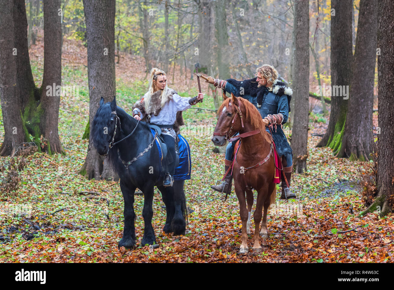 2 (2) Gefährliche skandinavischen Viking Krieger reiten Pferde und die Achsen über dem Kopf im Wald, bereit zu kämpfen. Northern Krieger Wikinger bereit, t Stockfoto