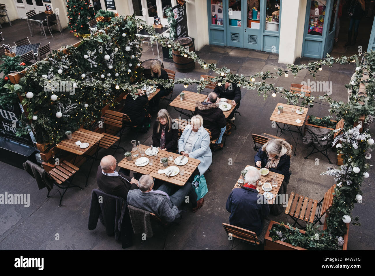 London, UK, November 21, 2018: Die Menschen sitzen unter Weihnachtsschmuck an Tischen im Außenbereich eines Cafés in Covent Garden Market, einer der am meisten Population Stockfoto