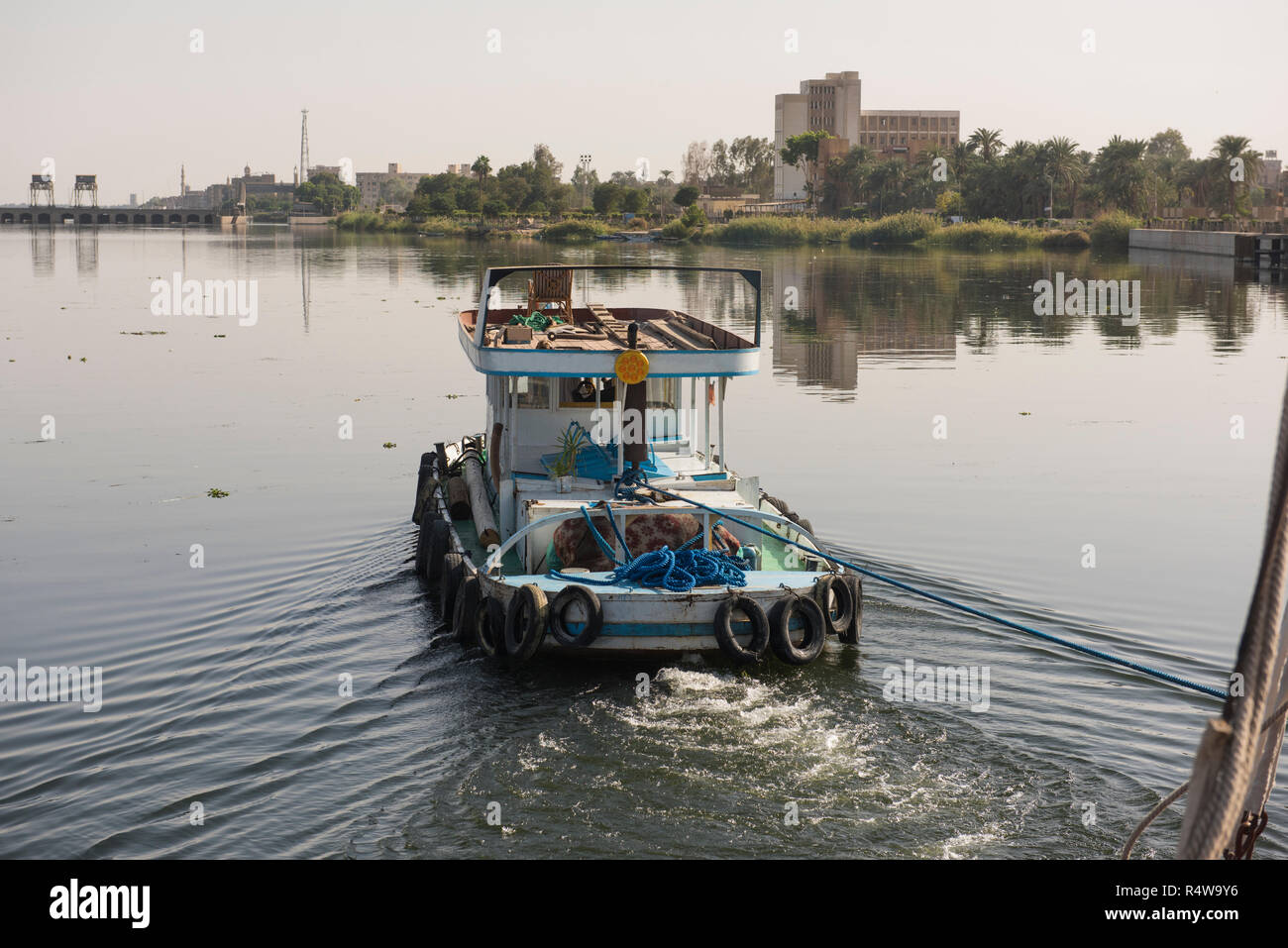 Kleine Schlepper abschleppen einer Yacht auf Nil in Ägypten durch ländliche Stadt Landschaft in Edfu Stockfoto